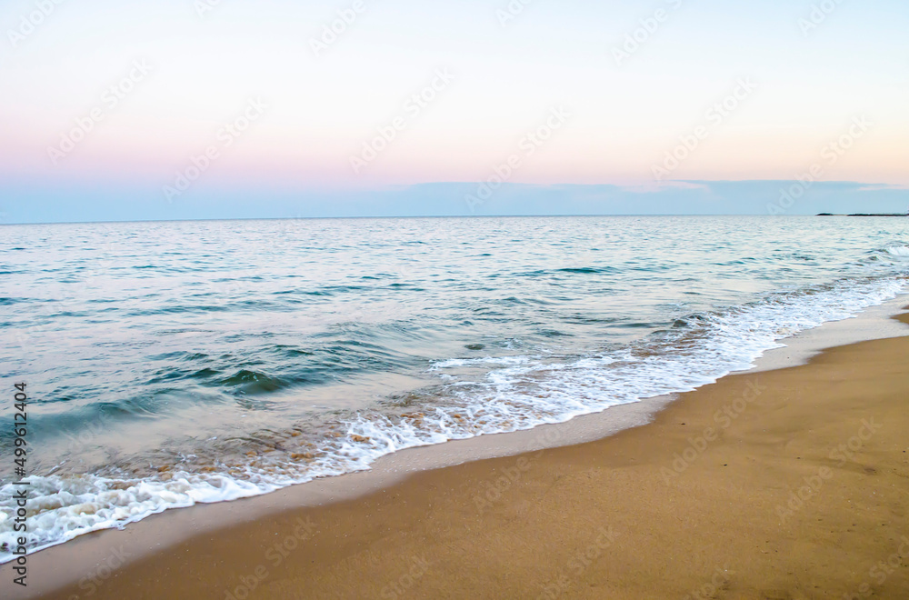 Obraz premium Summer evening at the seashore. View of the soft sea wave on the sandy beach.