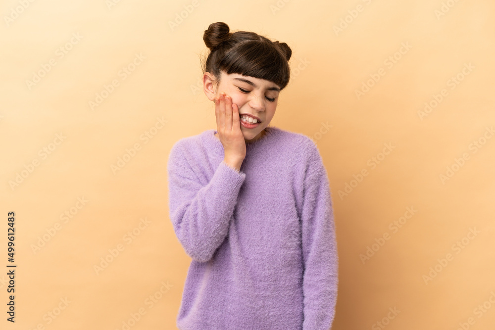 Little caucasian girl isolated on beige background with toothache Little caucasian girl isolated on beige background with toothache