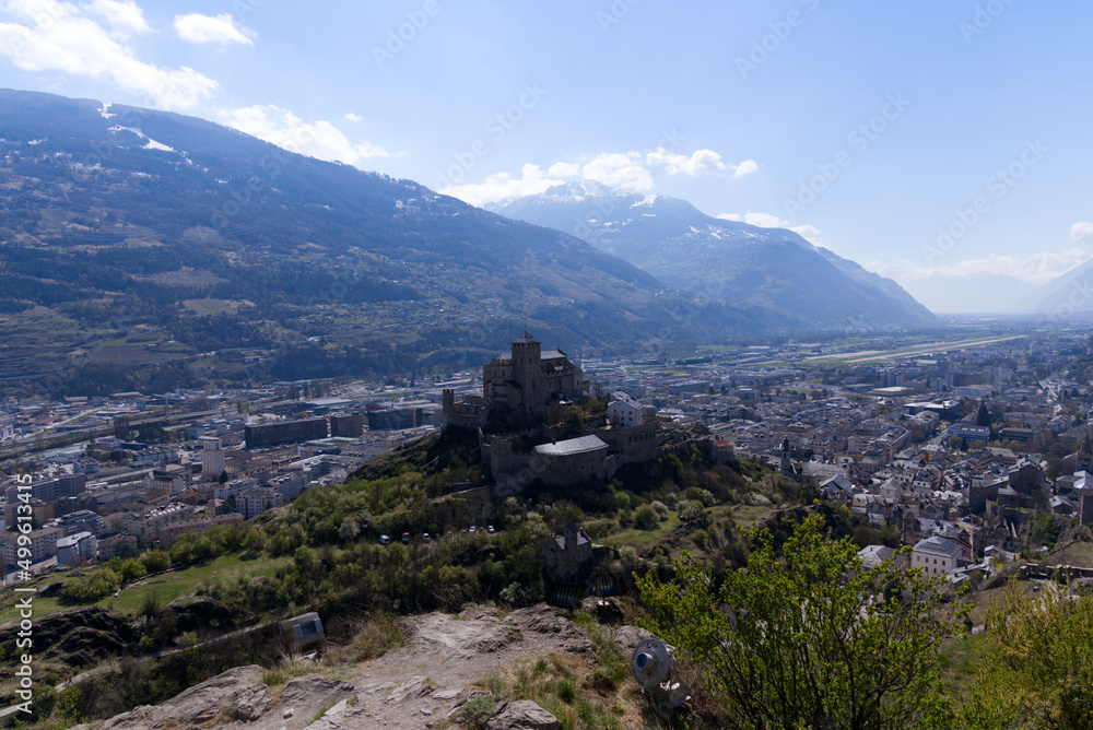 Aerial view with beautiful medieval catholic church and castle Basilique de Valère (Valeria) on a hill at City of Sion on a sunny spring day. Photo taken April 4th, 2022, Sion, Switzerland.