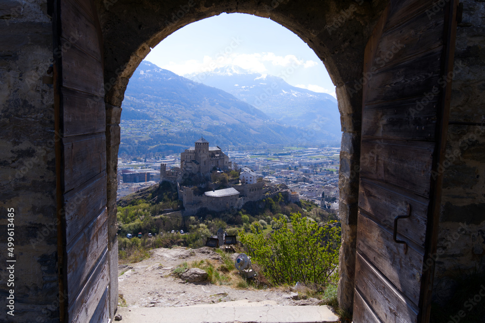 Beautiful view through stone arch of ruins of medieval Tourbillon Castle on a hill at City of Sion on a sunny spring day. Photo taken April 4th, 2022, Sion, Switzerland.