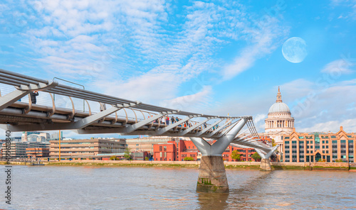 Millennium bridge and St. Pauls cathedral with full moon in evening light.