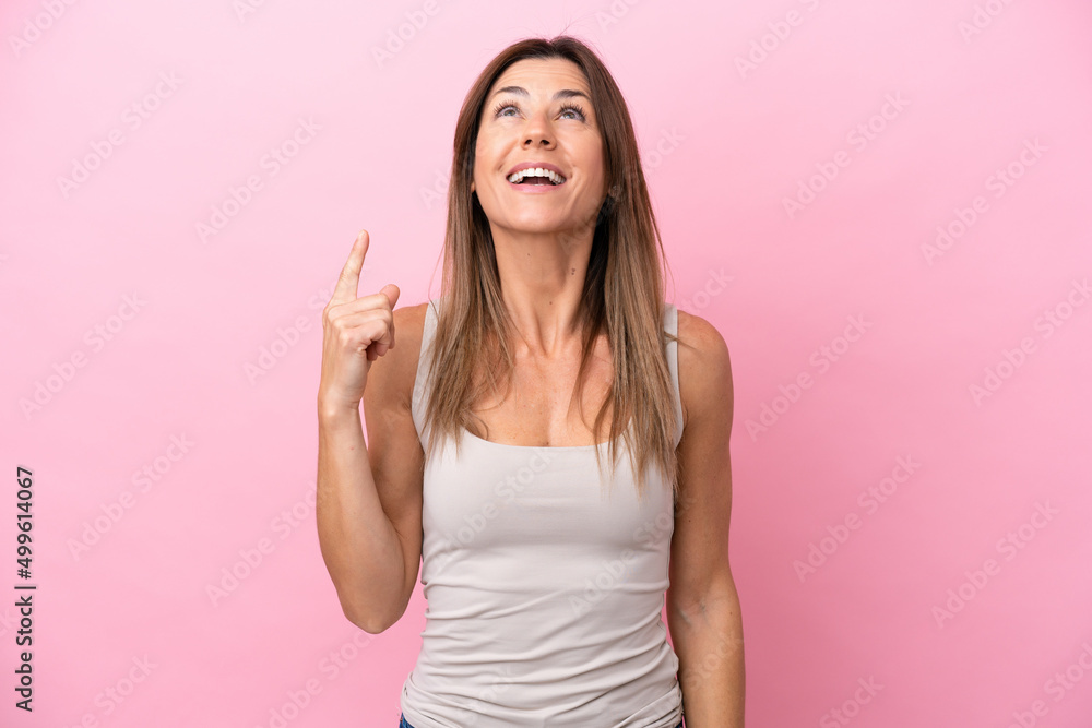 Middle age caucasian woman isolated on pink background pointing up and surprised Middle age caucasian woman isolated on pink background pointing up and surprised