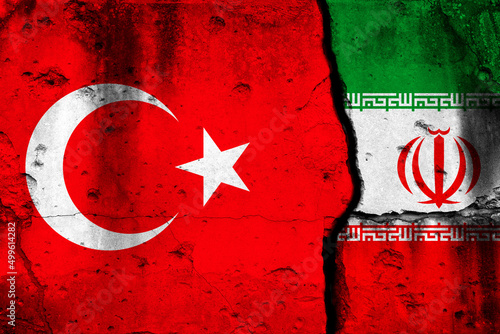 Turkey and Iran conflict, war concept. National flags background on cracked concrete wall