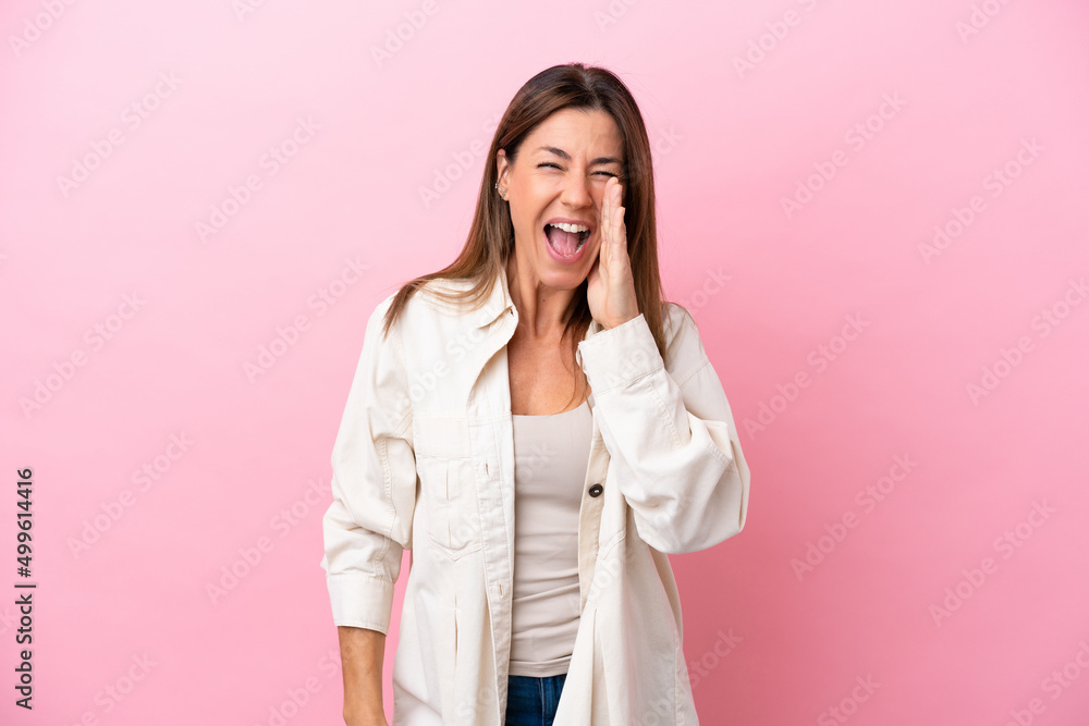 Middle age caucasian woman isolated on pink background shouting with mouth wide open Middle age caucasian woman isolated on pink background shouting with mouth wide open