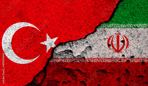 Turkey and Iran conflict, war concept. Flags background, cracked and damaged concrete wall