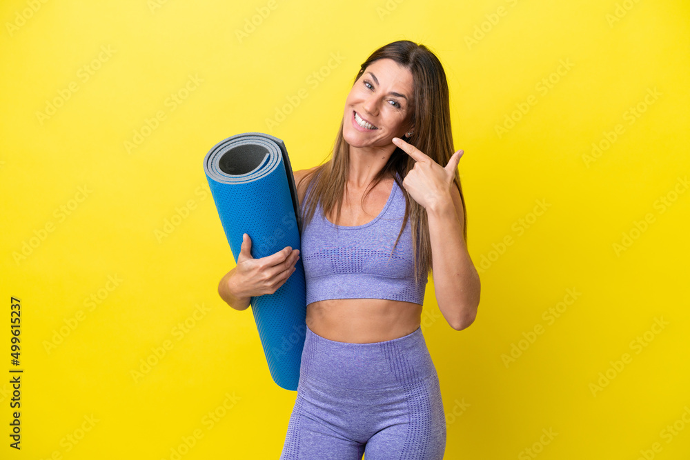 Sport woman going to yoga classes while holding a mat isolated non yellow background giving a thumbs up gesture Sport woman going to yoga classes while holding a mat isolated non yellow background giving a thumbs up gesture