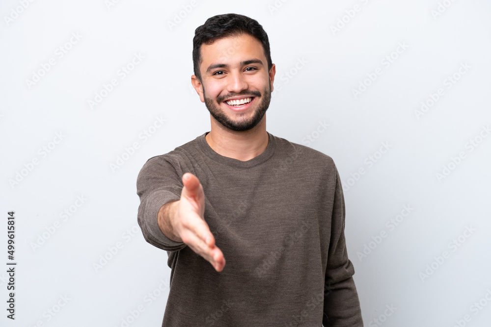 © luismolinero - Young Brazilian man isolated on white background shaking hands for closing a good deal