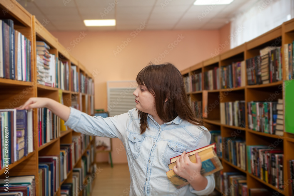 Happy schoolgirl reading a book in the library at school Happy schoolgirl reading a book in the library at school