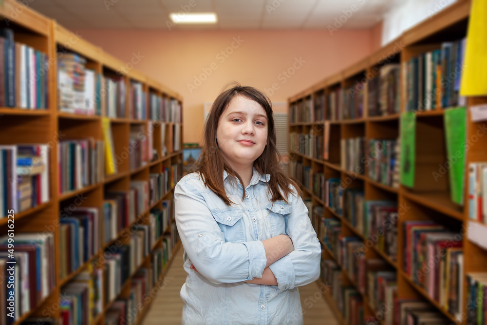 Happy schoolgirl reading a book in the library at school Happy schoolgirl reading a book in the library at school