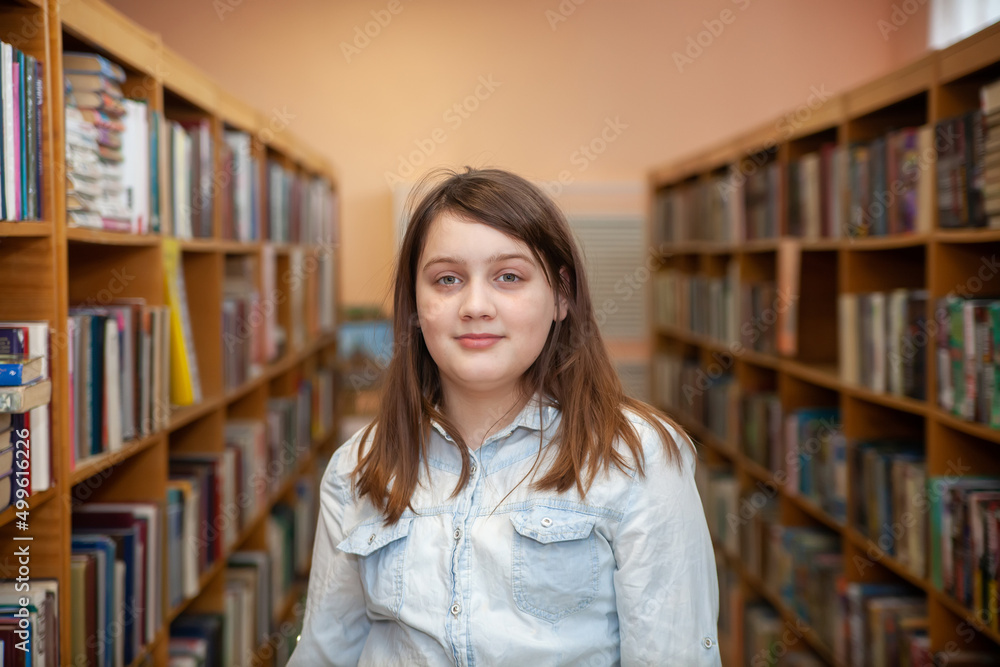 Happy schoolgirl reading a book in the library at school Happy schoolgirl reading a book in the library at school