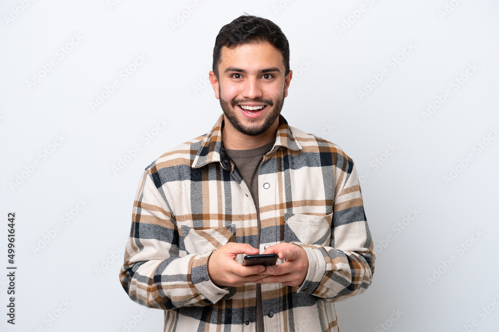Young Brazilian man isolated on white background surprised and sending a message Young Brazilian man isolated on white background surprised and sending a message
