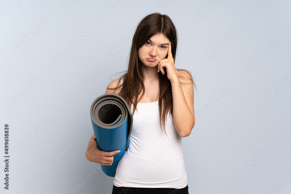 Young Ukrainian sport girl going to yoga classes while holding a mat thinking an idea Young Ukrainian sport girl going to yoga classes while holding a mat thinking an idea