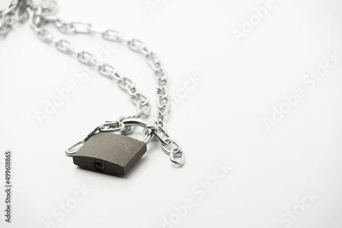 A metal chain with locked padlock on the white background symbolising closed access