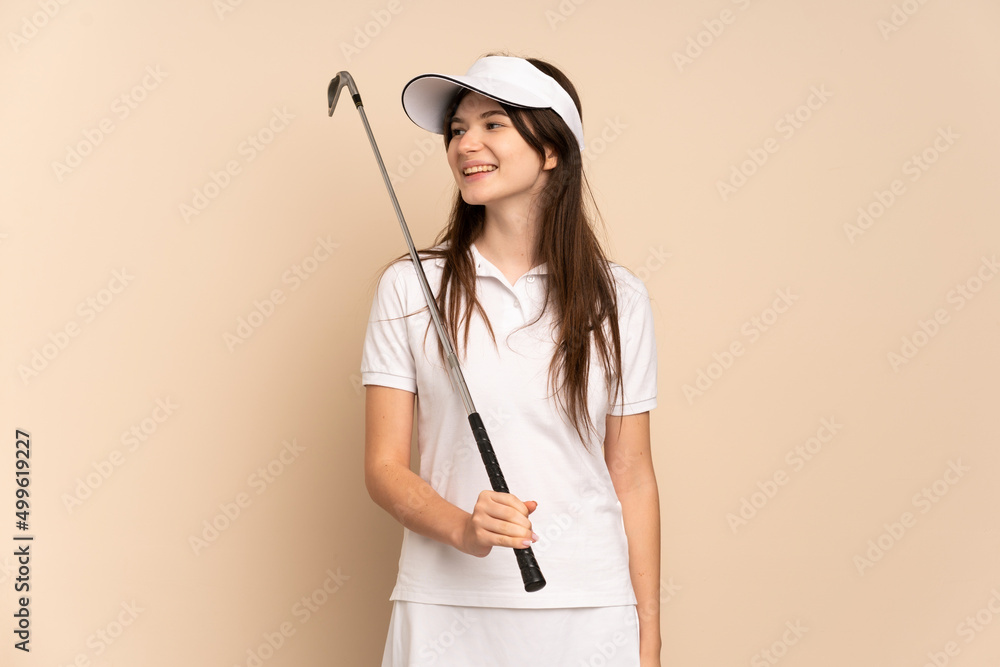 Young Ukrainian golfer girl isolated on beige background looking side Young Ukrainian golfer girl isolated on beige background looking side