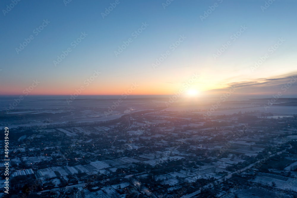 View of the village from a height, small private houses glowing in the evening, winter sunset
