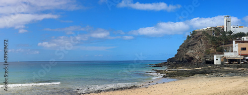 Cliffs at the end of beautiful morro jable beach on fuerteventura island under a blue cloudy sky photo