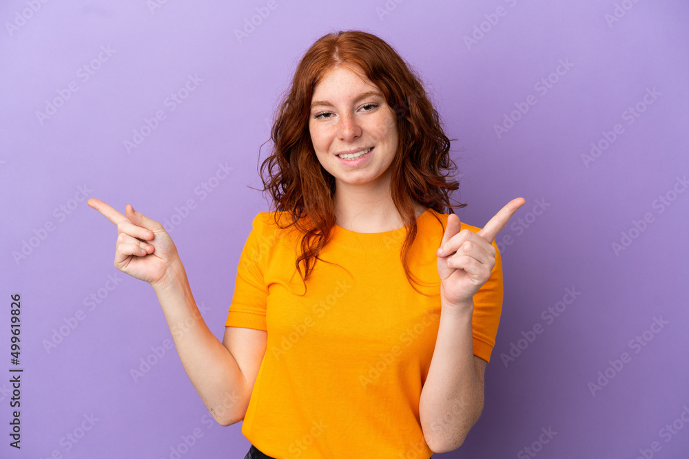 Teenager redhead girl over isolated purple background pointing finger to the laterals and happy Teenager redhead girl over isolated purple background pointing finger to the laterals and happy