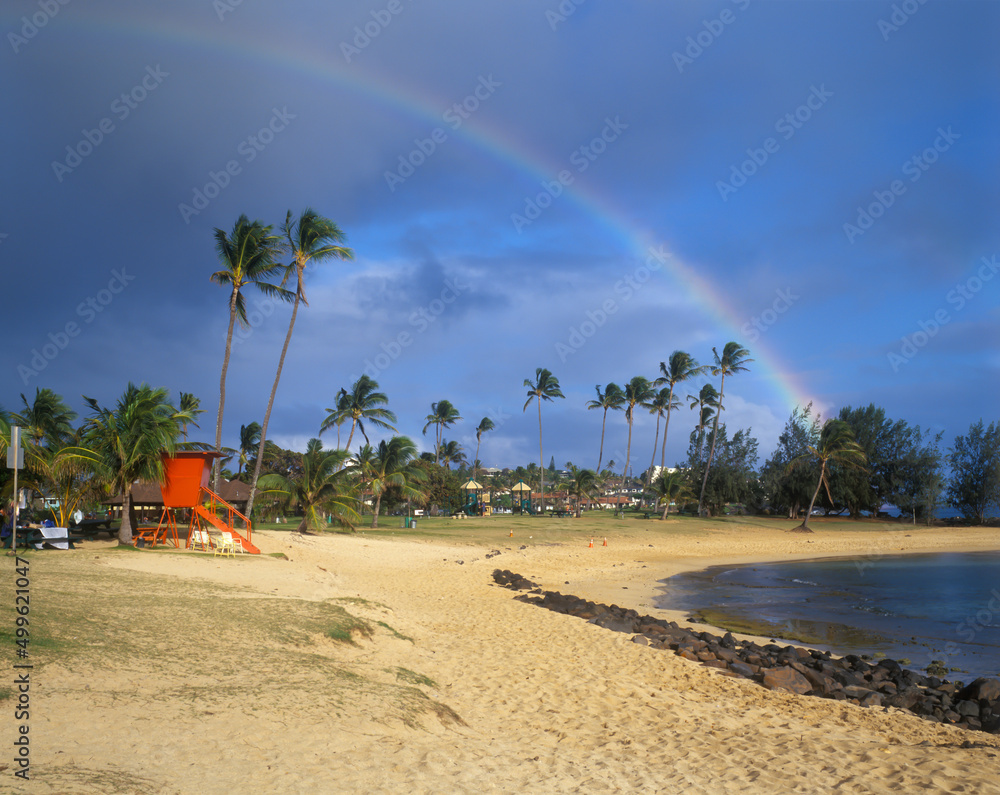 Poipu Beach and a rainbow. Note the old red lifeguard shade. They were