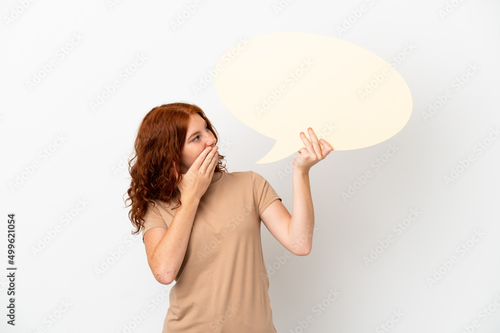 Teenager redhead girl isolated on white background holding an empty speech bubble with surprised expression Teenager redhead girl isolated on white background holding an empty speech bubble with surprised expression