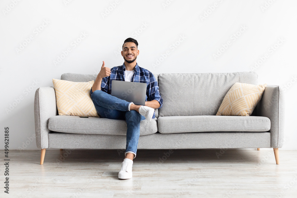 Portrait of smiling Arab man using laptop showing thumbs up