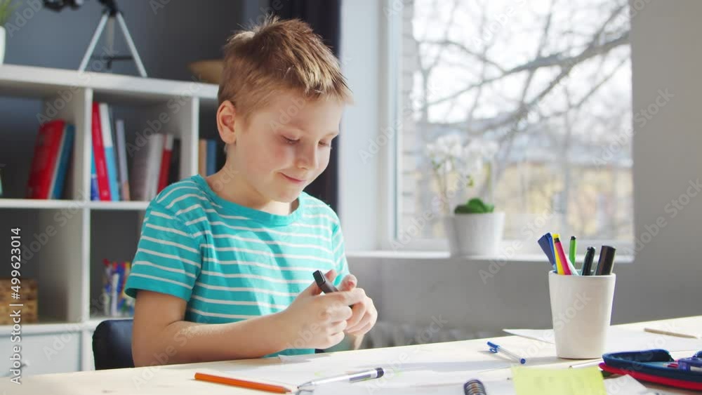 Boy is Doing his Homework at the Table. Cute Child is Learning at Home with the Help of Textbooks and School Materials. Study and Education Concept. Boy is Doing his Homework at the Table. Cute Child is Learning at Home with the Help of Textbooks and School Materials. Study and Education Concept.