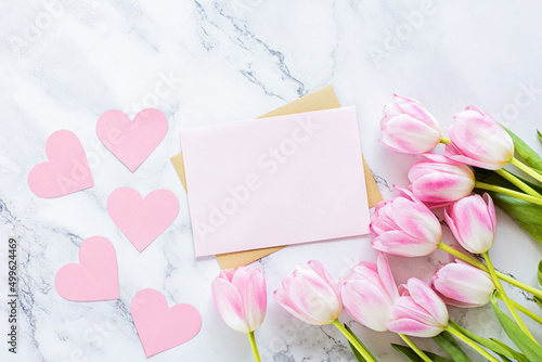 Greeting card for spring holiday, pink tulip flowers lying on white marble background with copy space. Flat lay top view Template for Mother's Day.