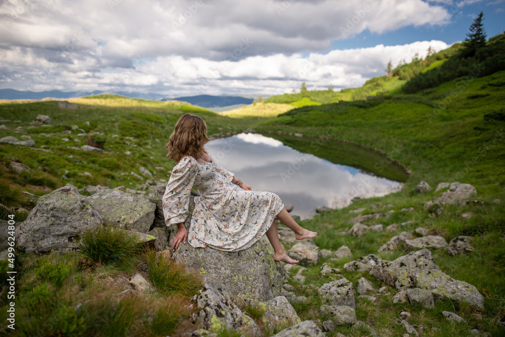 woman sitting on a rock and looling on a lake woman sitting on a rock and looling on a lake
