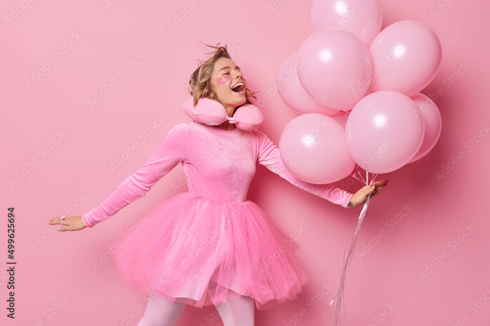 Glad positive woman has festive mood wears dress poses with balloons enjoys special occasion celebrates anniversary applies beauty patches to look young gets ready for party isolated on pink backgroud Glad positive woman has festive mood wears dress poses with balloons enjoys special occasion celebrates anniversary applies beauty patches to look young gets ready for party isolated on pink backgroud