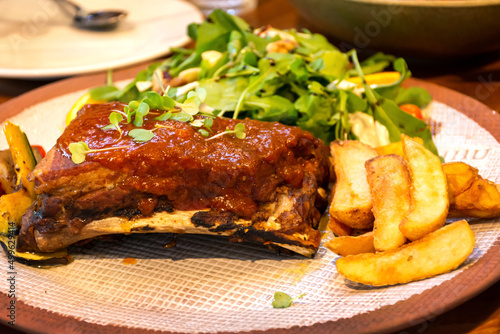Pork ribs grilled with BBQ sauce served with french fries and vegetables.