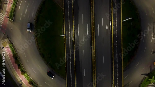 perspective of a busy highway at night and a roundabout below an elevated street photo