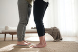 Two pairs of female legs. The teacher helps the student to stand on the board with nails. One foot is on the sadhu board