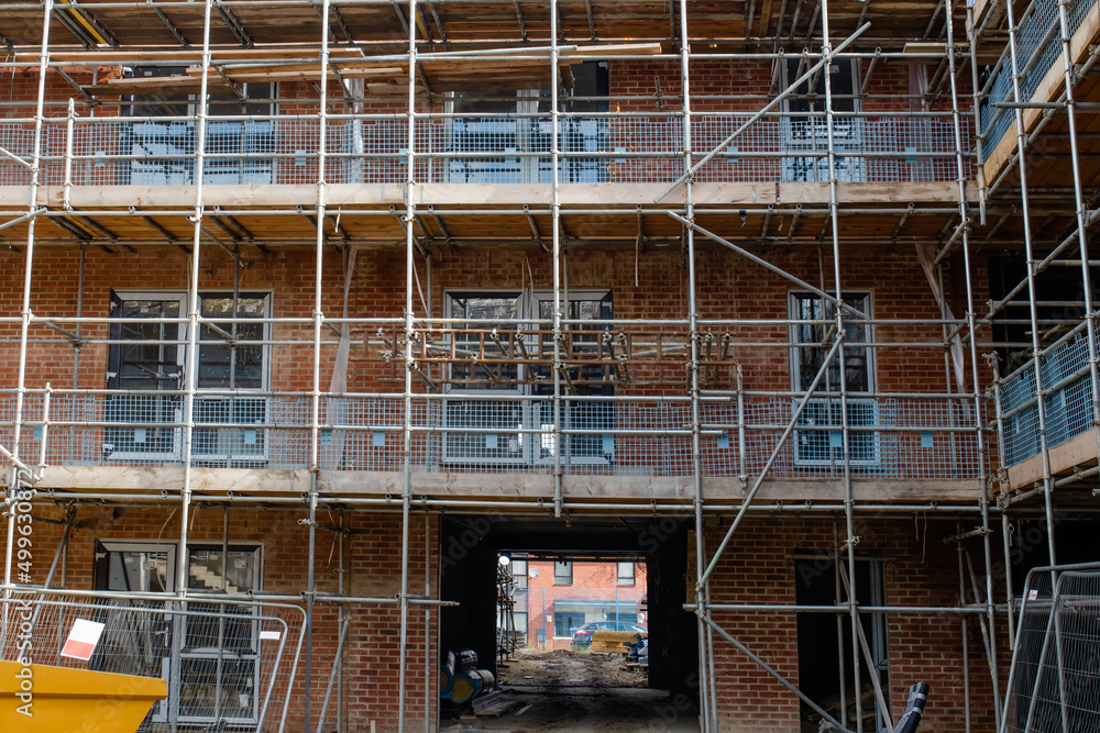 New build residential multistorey appartment building made of brick and concrete block, with scaffolds erected around it to provide access for .external construction works