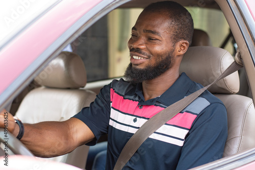 Fotografia young black man driving, with seatbelt on