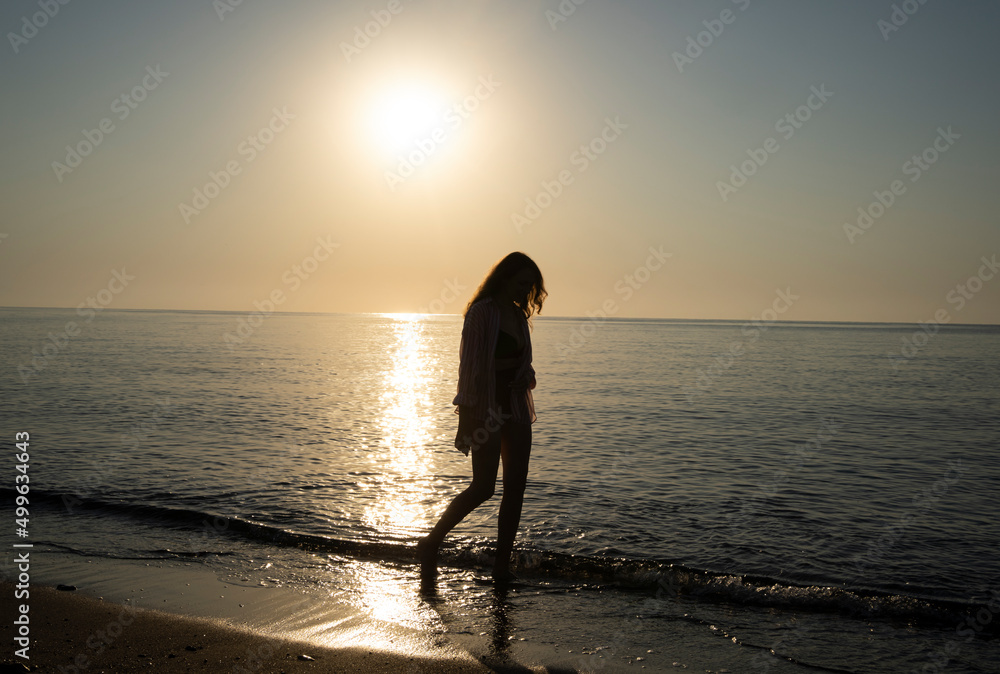 Girl walking along the beach at dawn