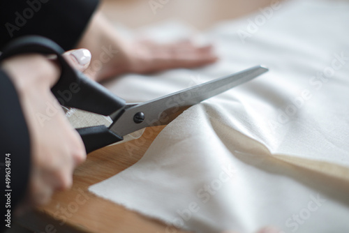 Female tailor hands using scissors to fabric, selective focus, natural light photo