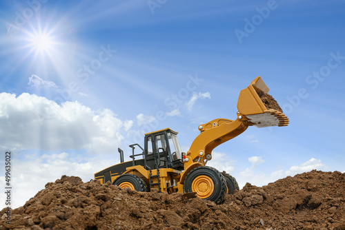 Wheel loader are digging the soil in the construction site on the sunbeam background .