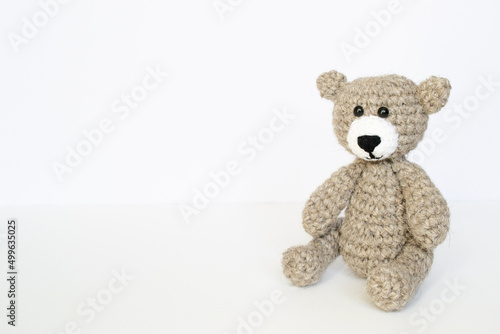 Crochet gray bear on white background. Crocheted bear