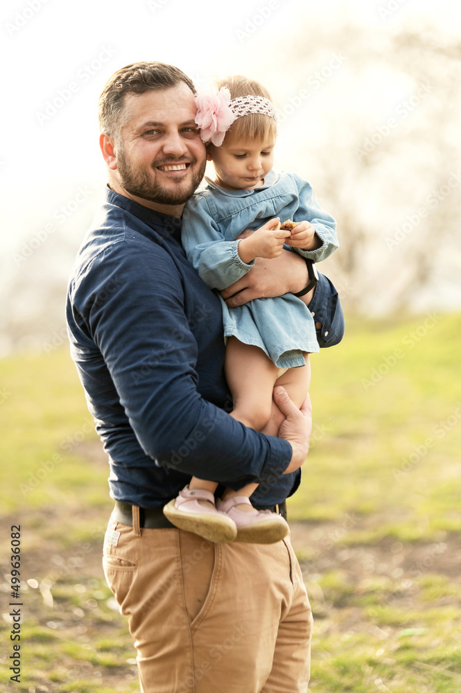 Fototapeta premium the father holds his daughter in his arms being in nature near the swing on the tree. rest at nature. happy father hugging daughter in ukraine.