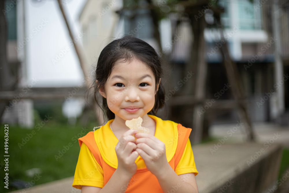 Happy asian girl in orange dress eating jelly candy. Happy asian girl in orange dress eating jelly candy.