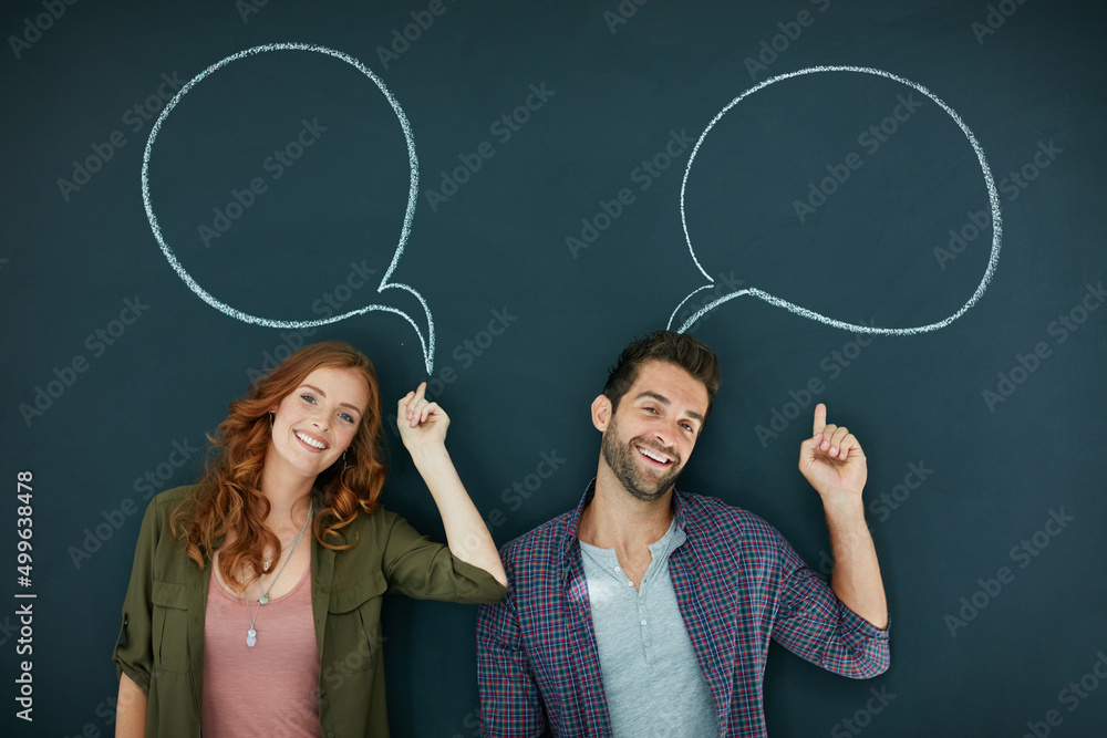 Making themselves heard. Portrait of a young couple standing in front of a blackboard with speech bubbles drawn on it.