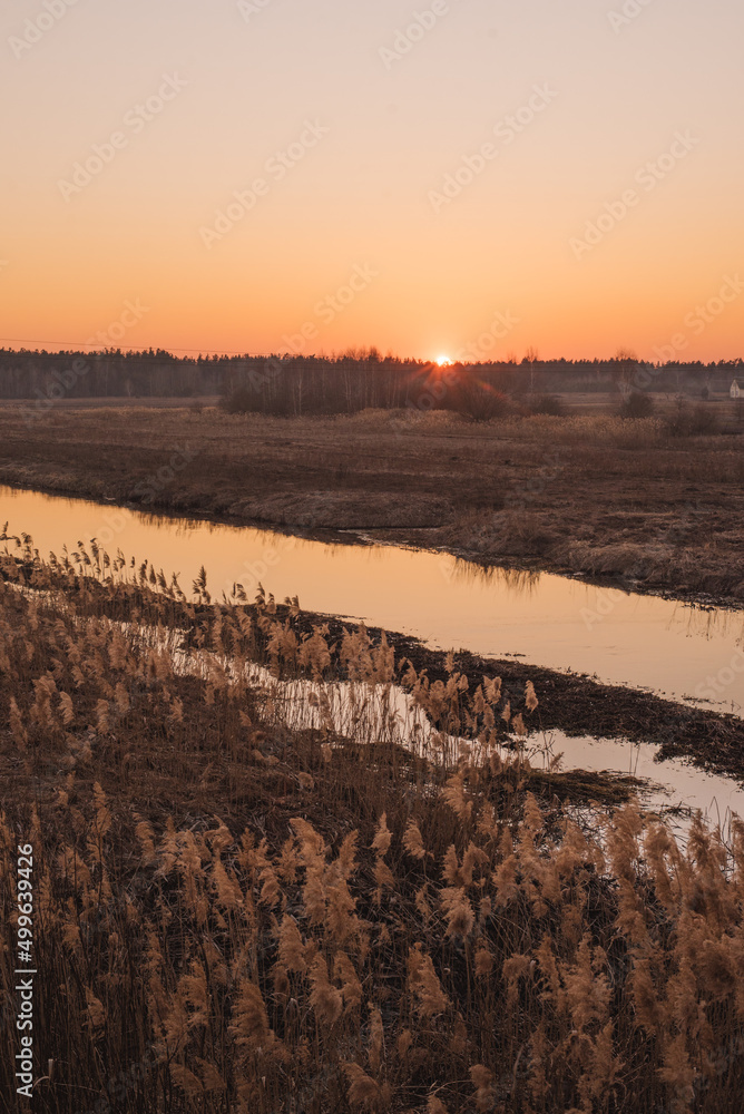 Sunset over narrow river in spring