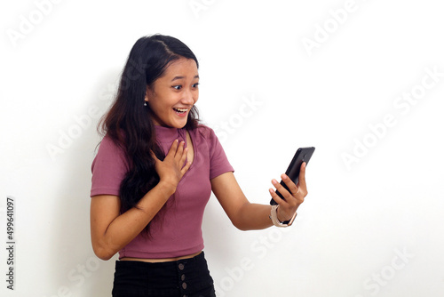Surprised young asian girl standing while getting a good news from her cellular phone