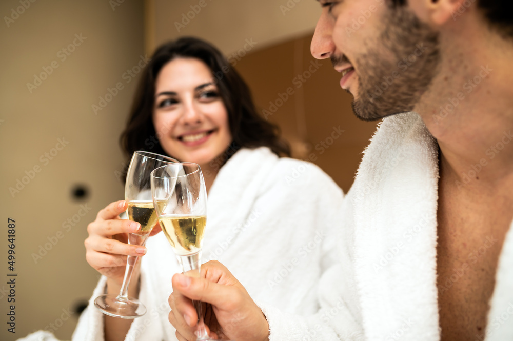 Cheerful couple in bathrobe toasting champagne glasses Cheerful couple in bathrobe toasting champagne glasses