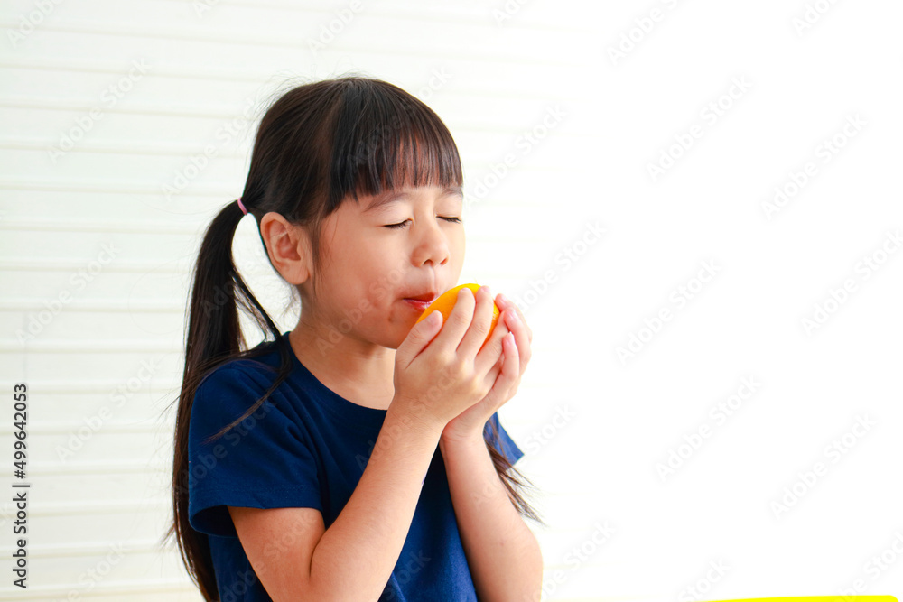Nutrition for school-age children. Cute little Asian girl enjoys eating oranges. Choosing the right food according to the age of the child for good health Nutrition for school-age children. Cute little Asian girl enjoys eating oranges. Choosing the right food according to the age of the child for good health