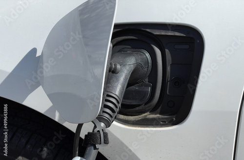 Close up of an EV connector plug charging an electric car. No people