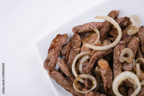 Portion of filet mignon with onion on top on light background (ID: 499644464)
