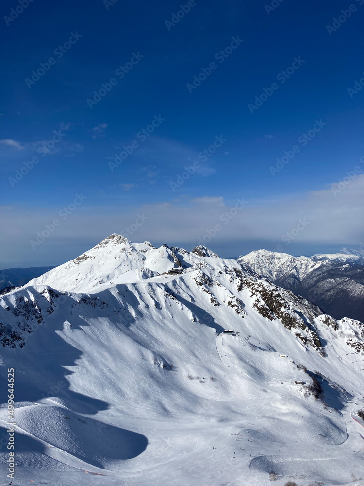 Peak of winter mountain with snow and blue sky background