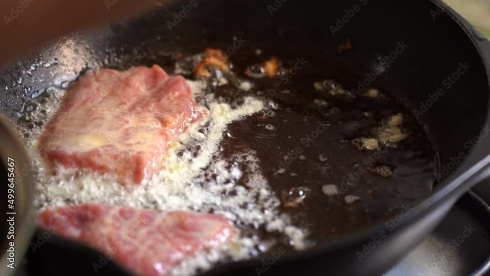 Meat chops in batter are placed in hot frying pan. Meat is fried in oil. Meat chops in batter are placed in hot frying pan. Meat is fried in oil.
