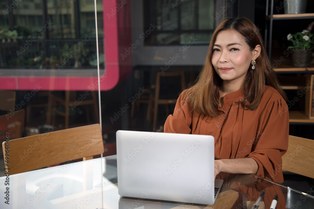 Yonug Asian adult brown hair woman sitting in cafe smiling and typing using laptop.internet communication. Yonug Asian adult brown hair woman sitting in cafe smiling and typing using laptop.internet communication.