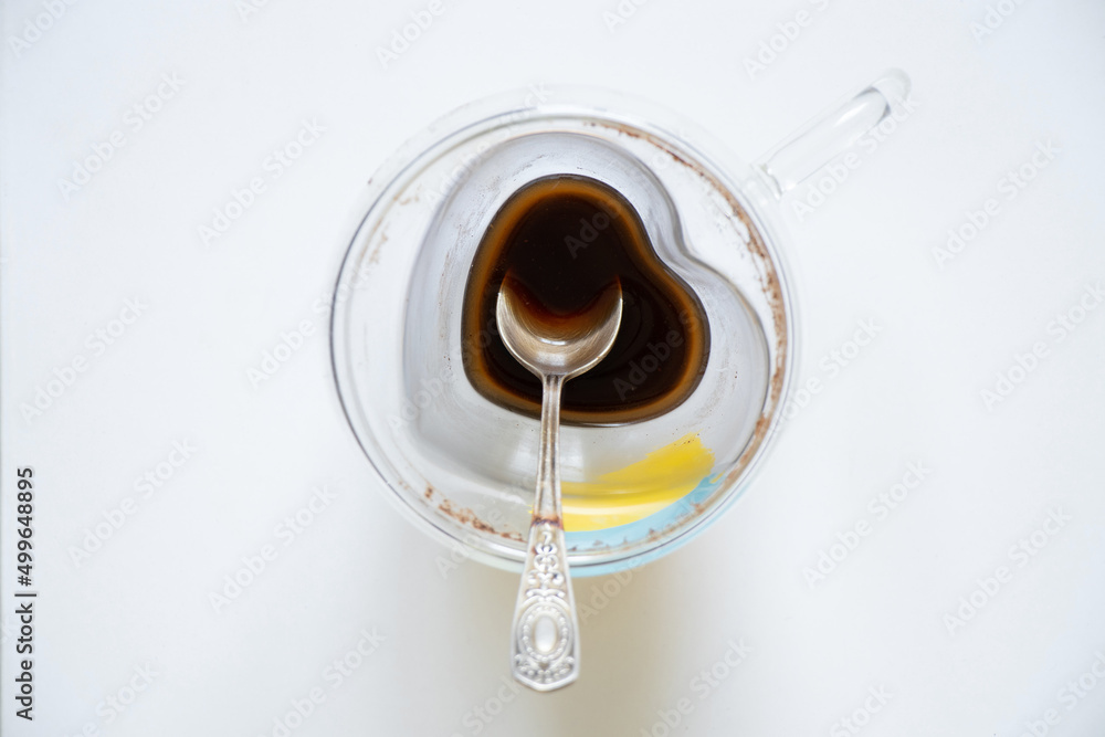 A cup of coffee with an unfinished drink on a white table top down and a teaspoon , coffee